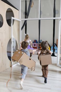 Joyful kids playing indoors with creative cardboard costumes.