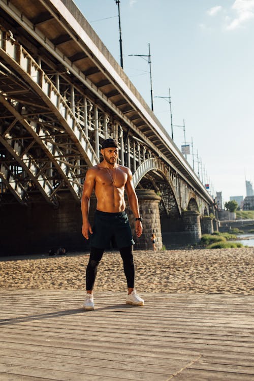 A Shirtless Man With Muscular Body Standing Near A Bridge