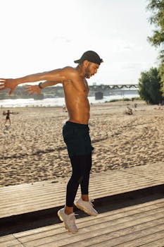 Muscular man performs exercise on a sunny beach wooden deck.