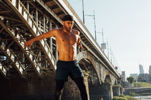 Free A fit man engages in an enthusiastic outdoor workout under a city bridge during the day. Stock Photo