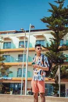 Young man posing confidently in sunny Essaouira, Morocco, wearing a stylish outfit and sunglasses.