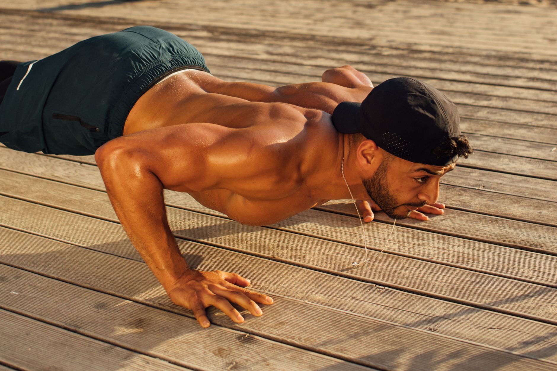 Shirtless man performing push-ups outdoors on a sunny day, showcasing strength and fitness.