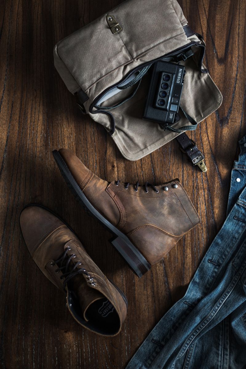 Leather boots with a camera and denim on rustic wood