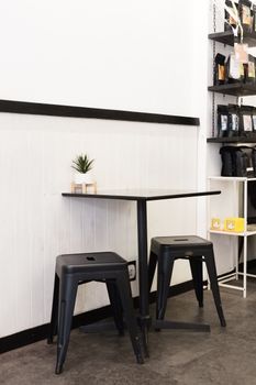 Minimalist coffee shop corner with metal stools and black table.