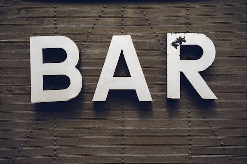 Foto de archivo de un letrero antiguo de bar en una pared de madera