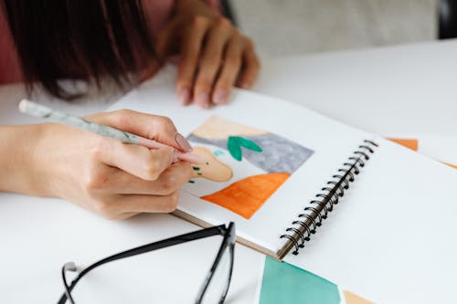 Close-Up Shot of a Person Writing on a Sketchbook