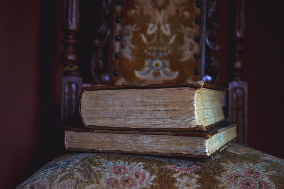 Antique leather-bound books stacked beside a calligraphy pen and tea cup representing dark academia baby name aesthetics