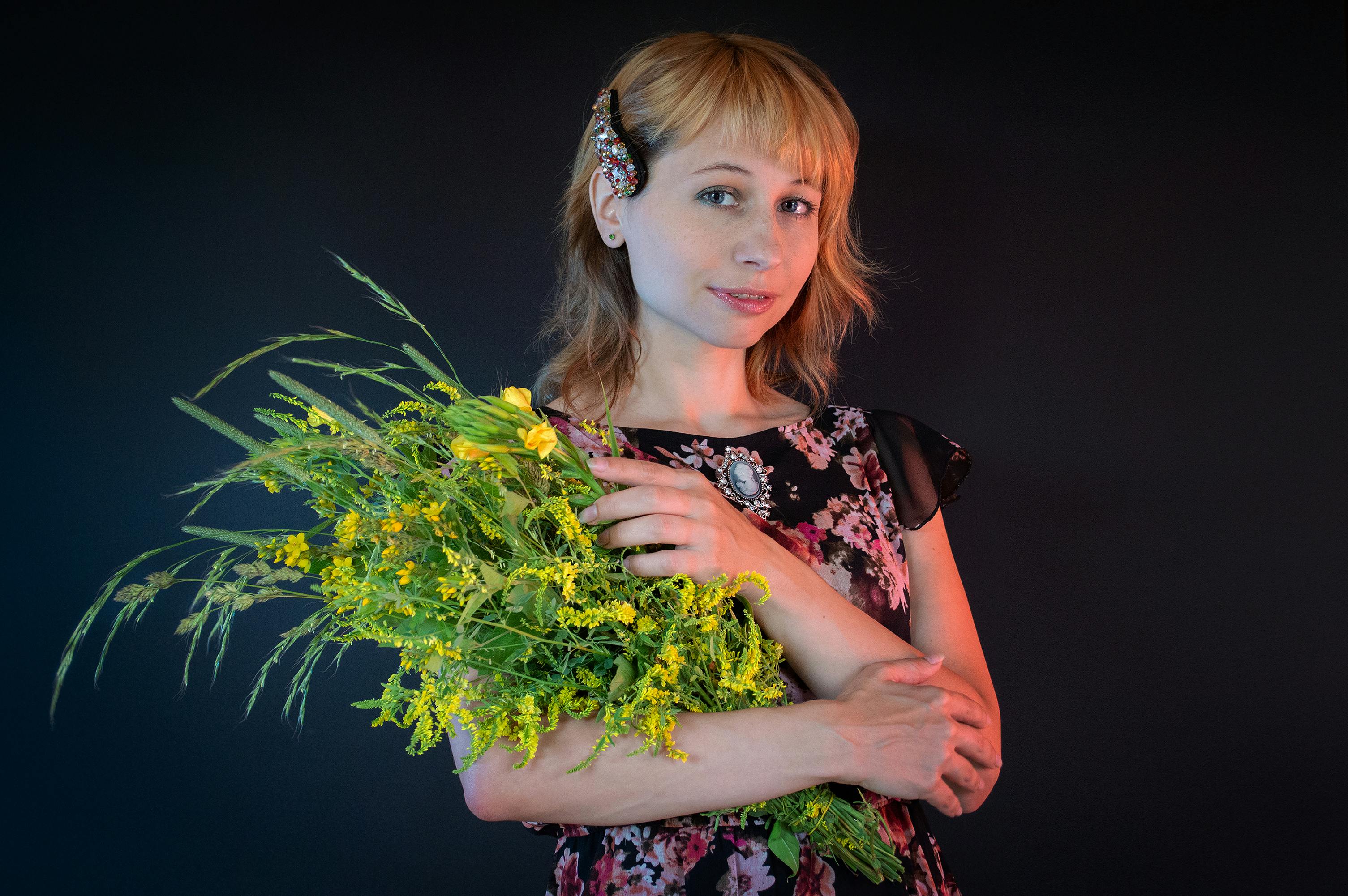 woman in black and pink floral dress holding yellow flowers