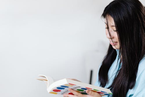 Close-Up Photo of a Woman with Long Black Hair Reading a Book