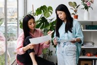 2 Women Holding White Printer Paper