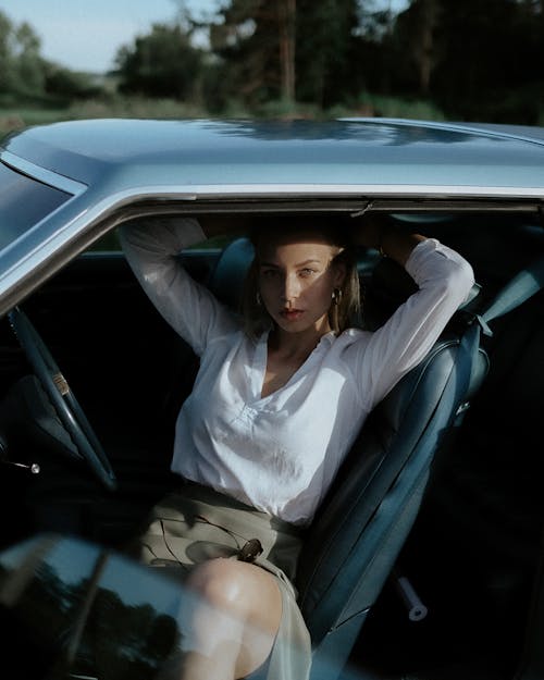 Woman in a White Long Sleeve Shirt Posing Inside a Car