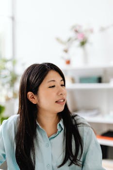 A candid portrait of a woman with long hair in an office environment, looking aside.