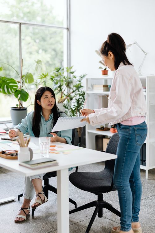 Free Two Asian women engaging in collaboration at a modern office. Bright and productive atmosphere. Stock Photo