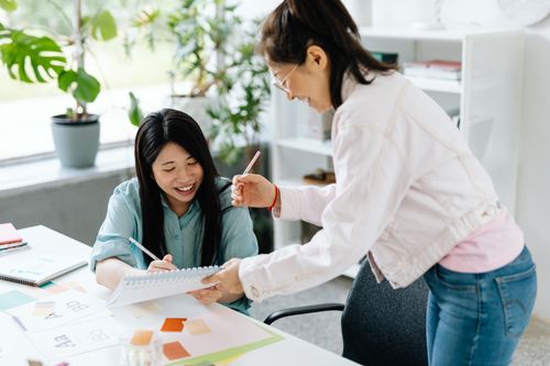 Free Two colleagues enjoying a collaborative work session in a modern office setting with natural light. Stock Photo