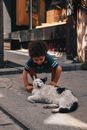 Boy in Black T-shirt and Blue Denim Shorts Sitting on Concrete Floor With White and