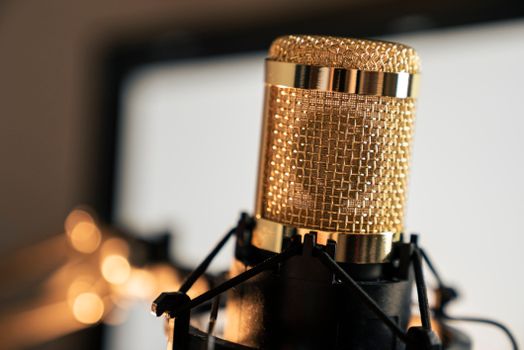 A golden condenser microphone used for professional recording in a studio setting.