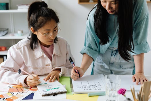 Two Asian women engaging in brainstorming and planning session in a modern office setting.