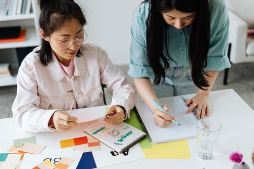 Free Two women collaborate on design ideas at a desk, emphasizing teamwork and creativity. Stock Photo