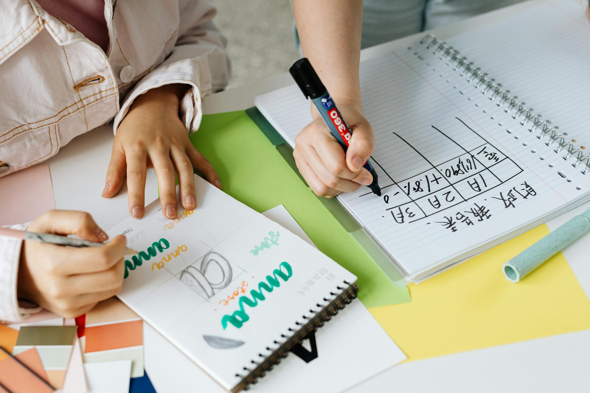 Two people collaborating on design ideas with colored pens and notebooks.