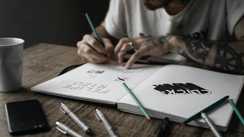 Person Writing on Sketchbook