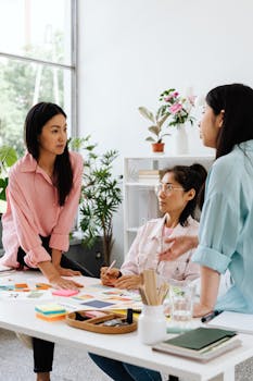 Three women brainstorming around a table in a modern office with plants.