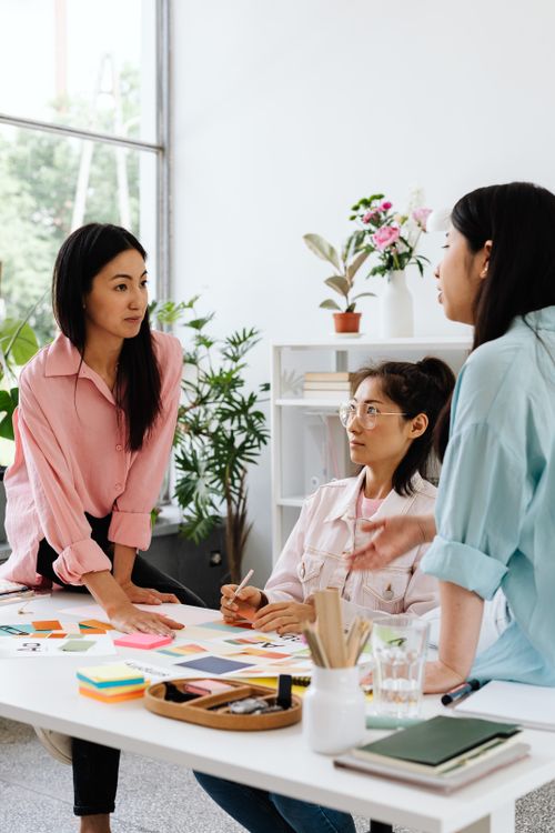 Free Three women brainstorming around a table in a modern office with plants. Stock Photo