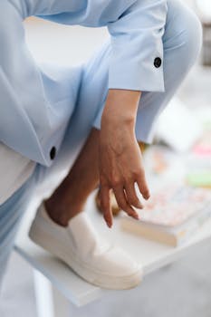 Close-up of a person wearing a blue suit and white sneakers, striking a stylish pose.