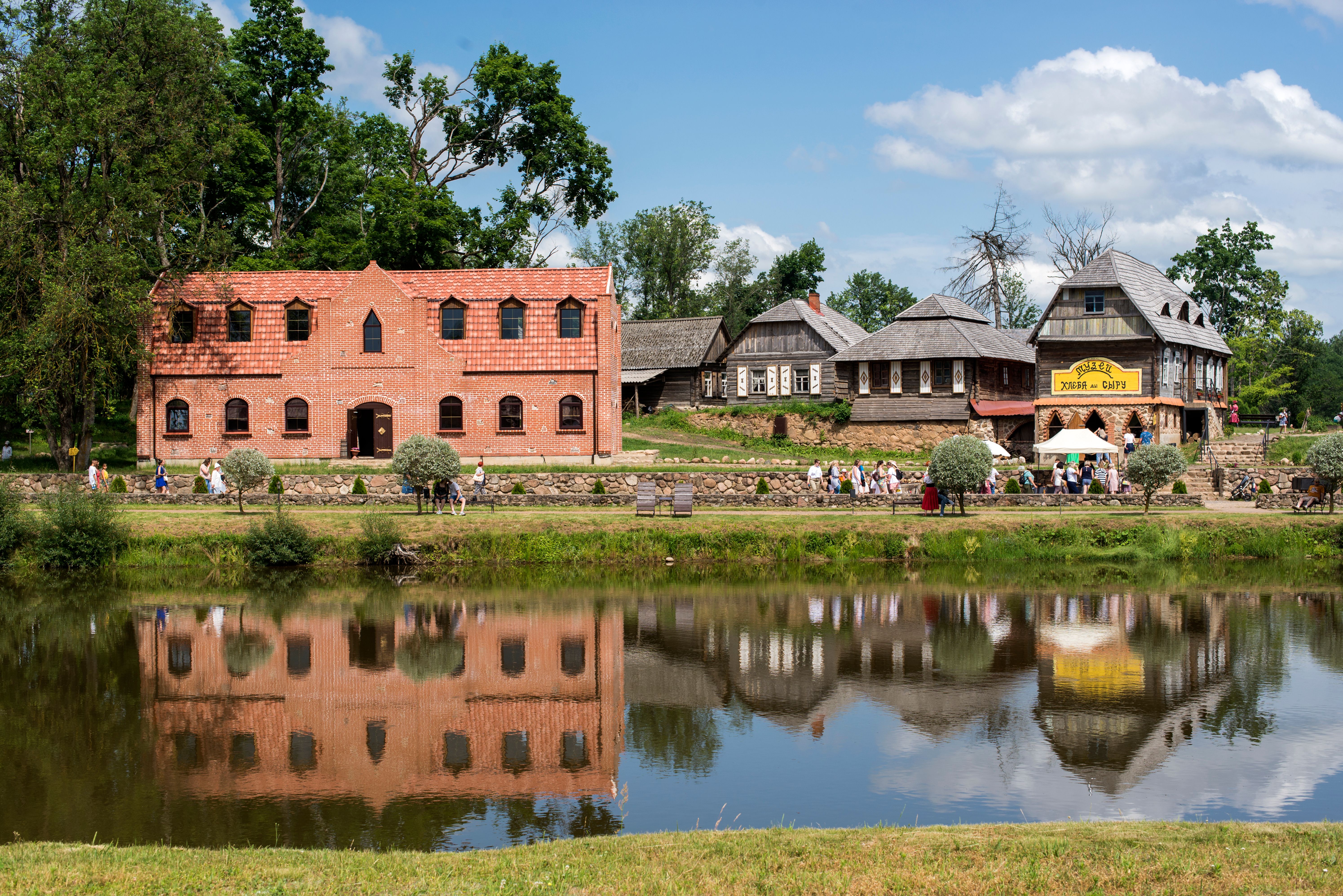 Explore quaint village life with reflections of traditional architecture along a serene river.