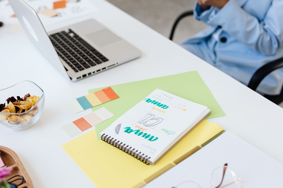 Modern workspace setup with laptop, notebook, and color swatches for design inspiration.