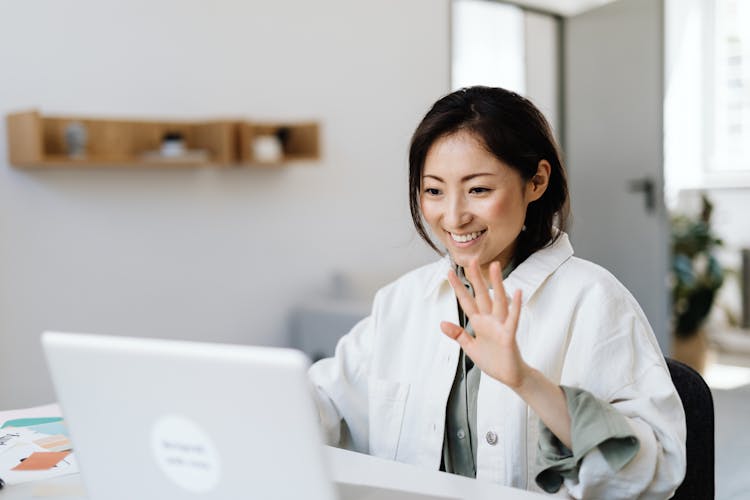 A Woman Waving At The Laptop