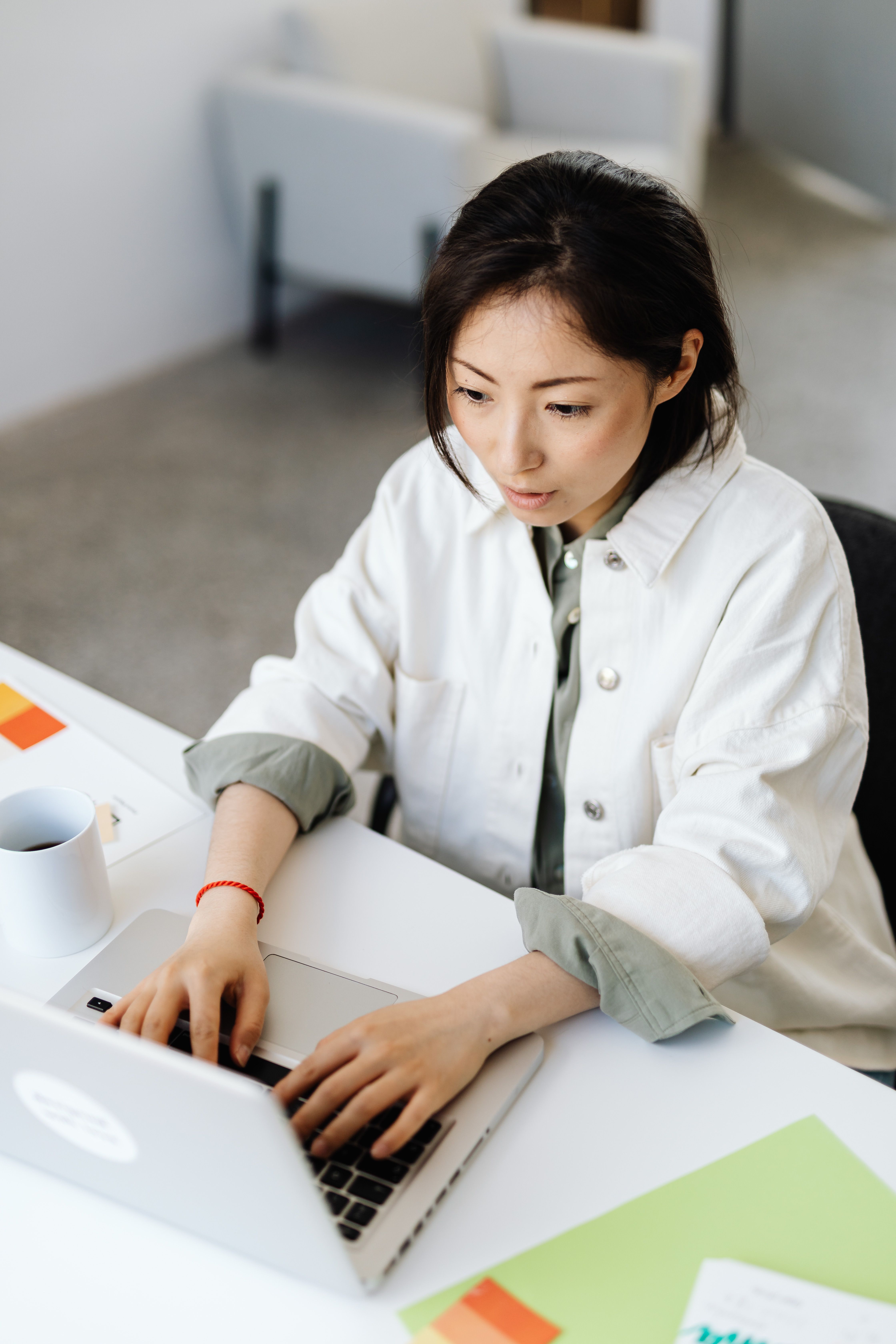 Woman in White Jacket Typing on Her Laptop