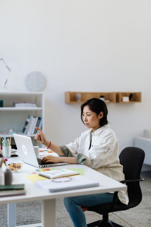 Free Professional Asian woman focused on laptop work in a modern and minimalistic office setting. Stock Photo