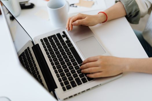 Close-up of hands working on a laptop with coffee mug on desk, indoors workspace.