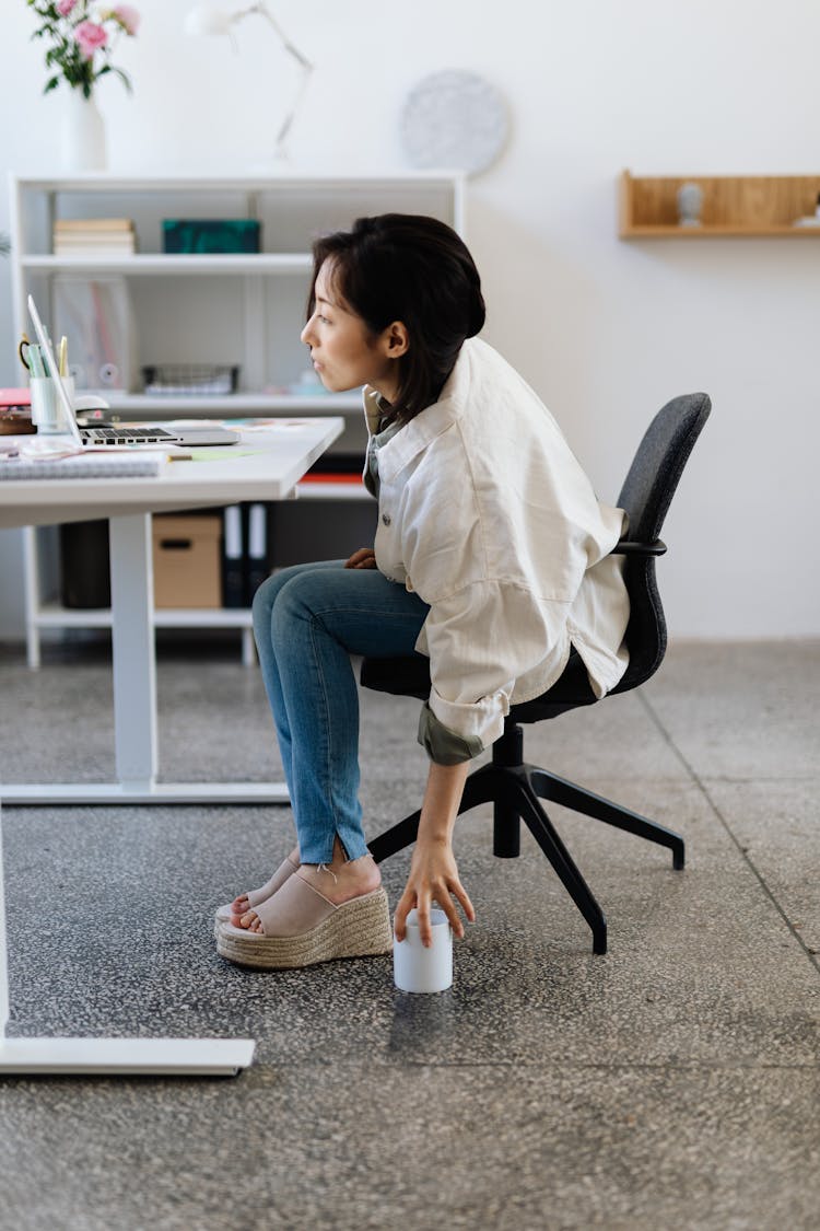 A Woman Picking Up A Mug From The Floor