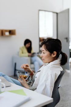 Woman enjoying breakfast in modern office environment, promoting work-life balance.