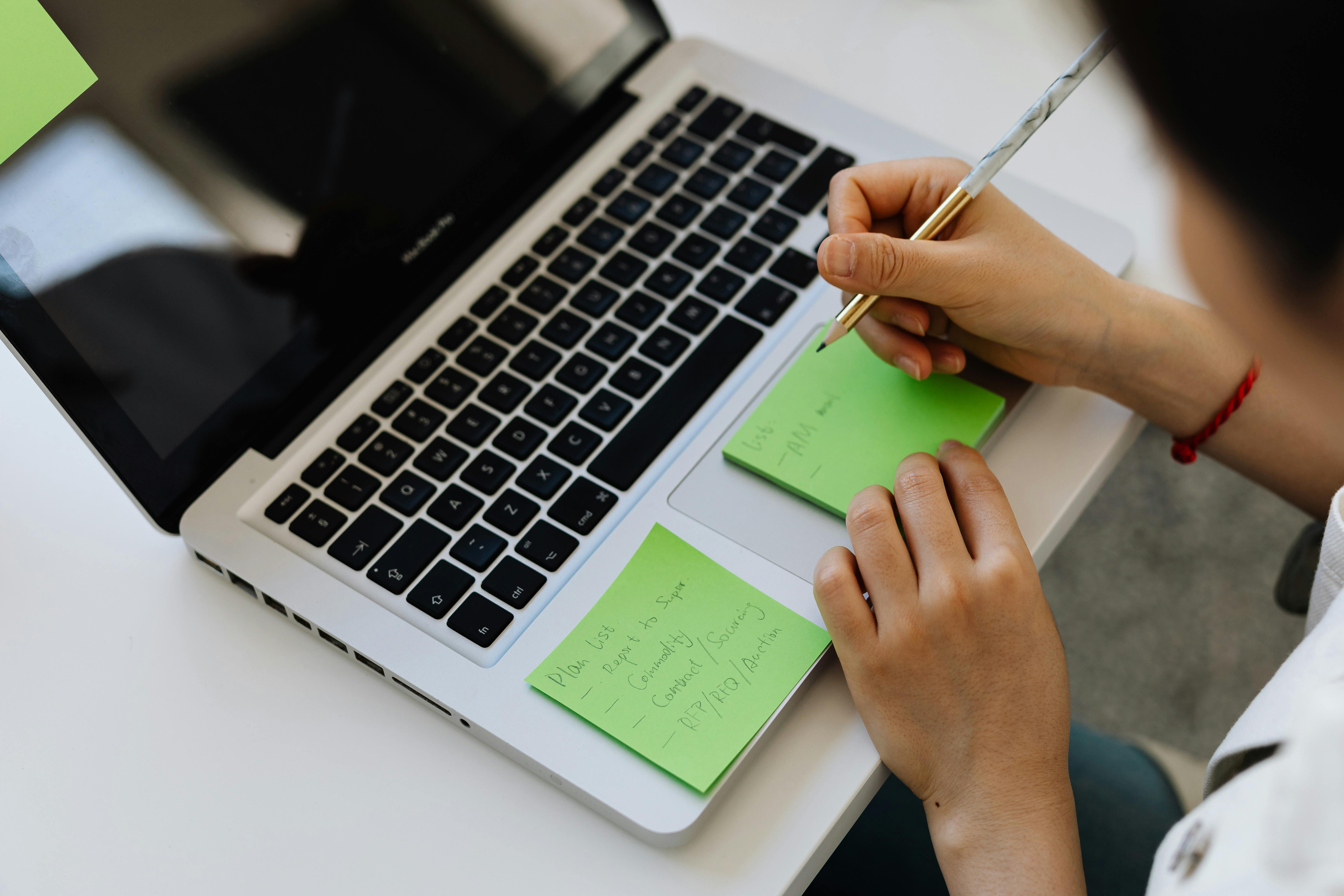 person writing on green sticky notes