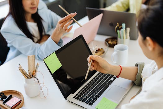 A diverse group of young professionals collaborating around laptops in a modern office setting.
