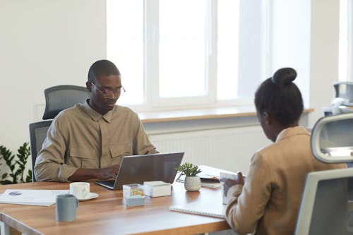 A Man Sitting on a Chair Using a Laptop on a Wooden Table