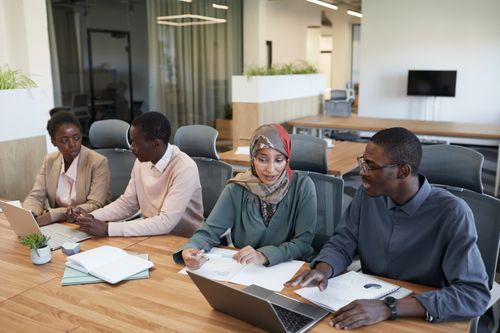 Free A diverse group of professionals working together at a wooden table in a contemporary office setting. Stock Photo