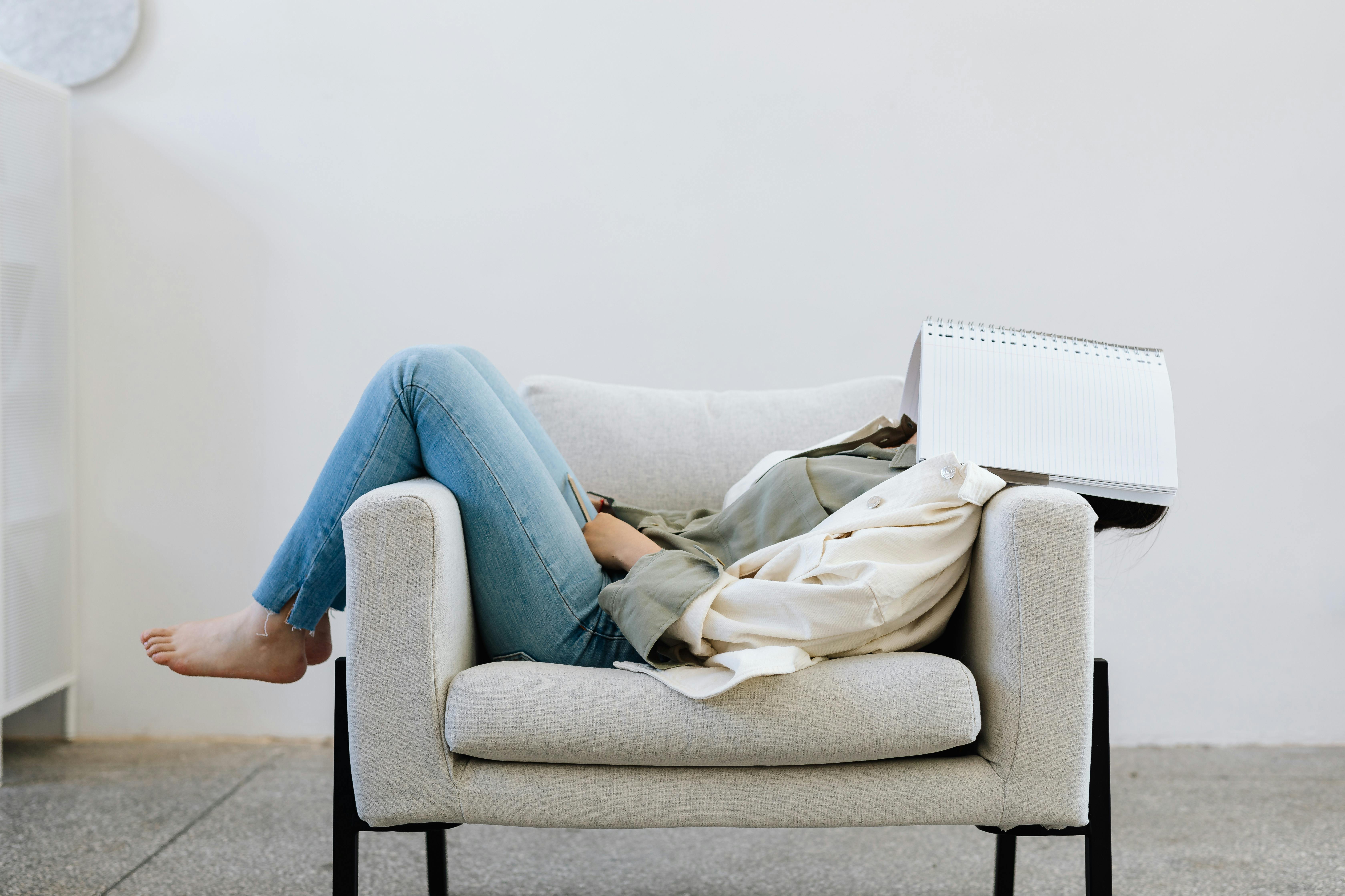 Person Lying on Sofa Chair Face Covered with Notebook Free Stock