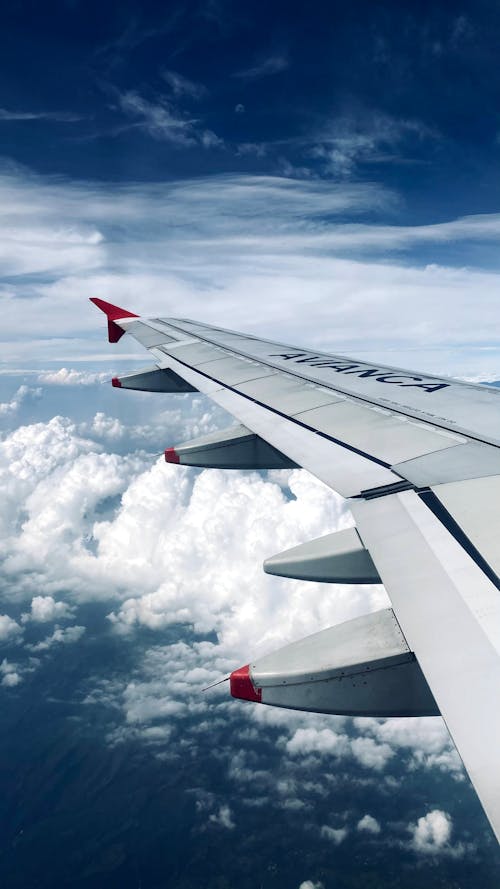Free White and Red Airplane Wing Under White Clouds Stock Photo