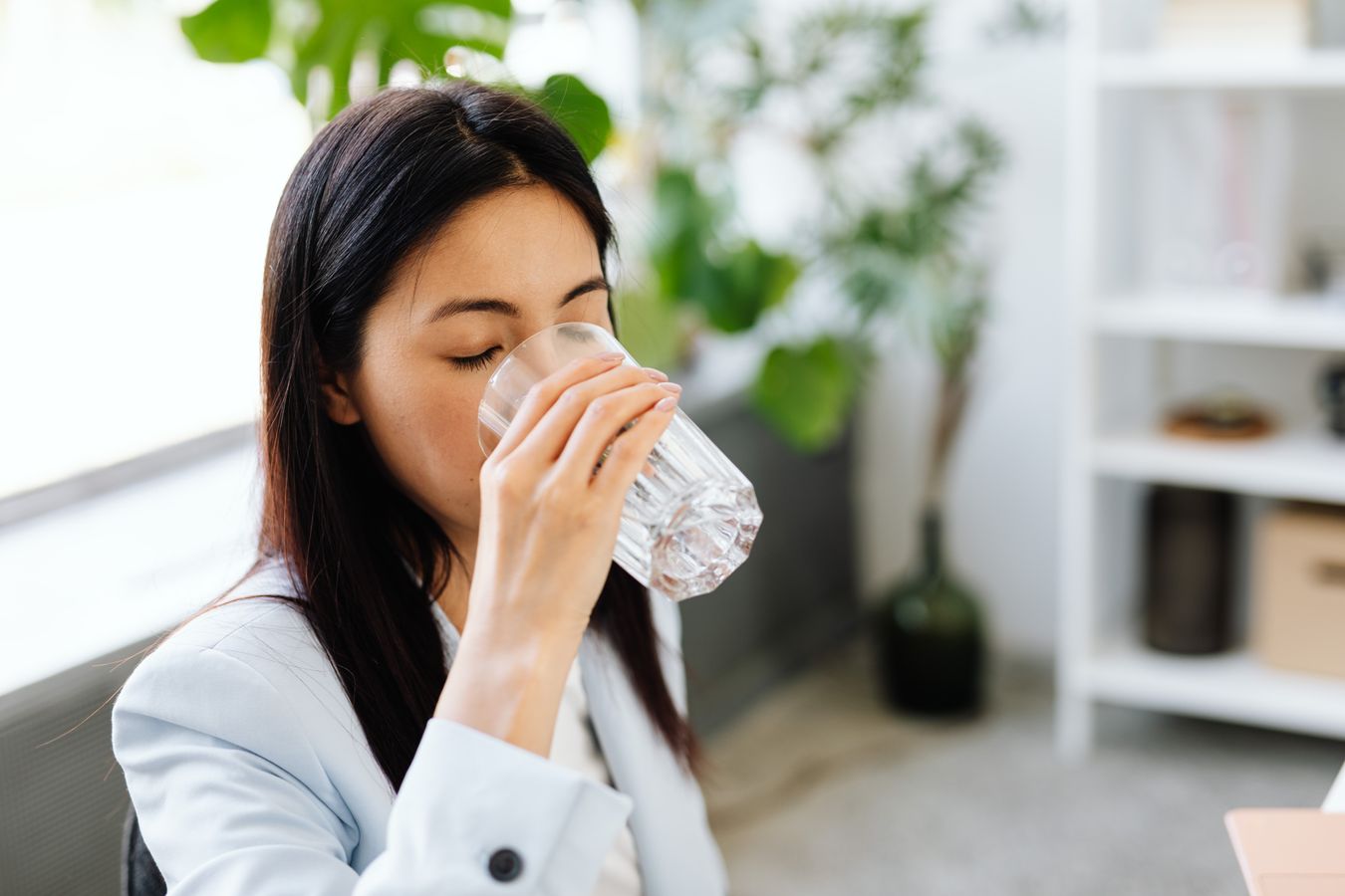 Professional woman sipping a glass of water at her modern office desk