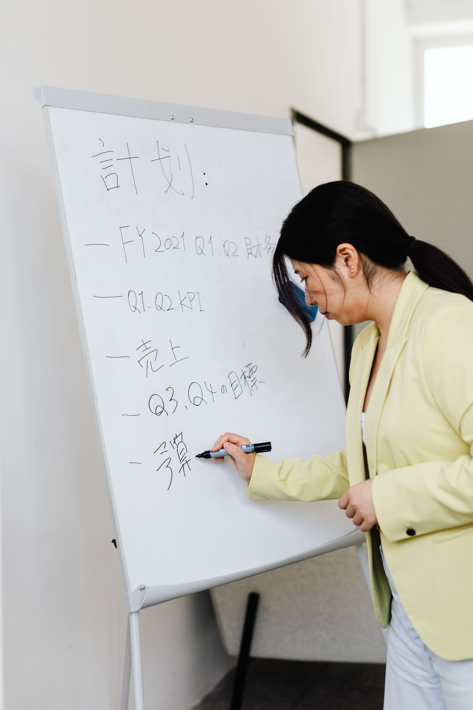 研修でホワイトボードに書くアジア系の女性