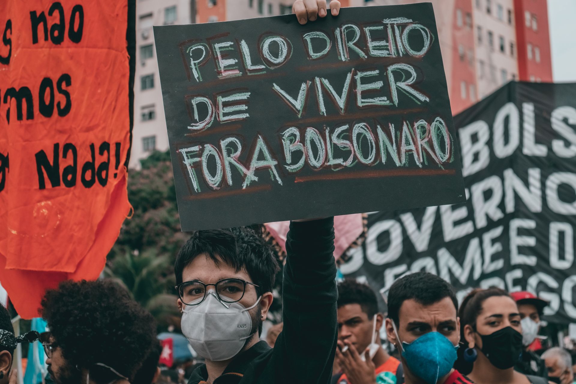 Protesters in Rio de Janeiro hold signs and wear masks demanding political change.