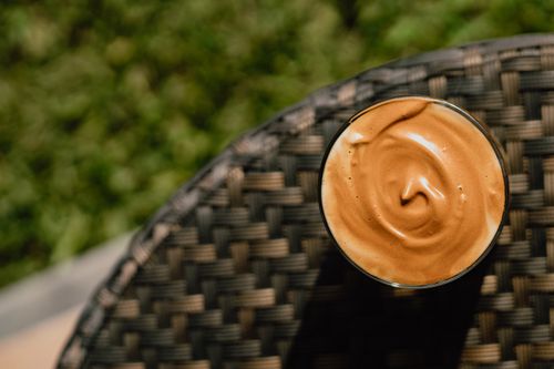 Free High-angle shot of a frothy Dalgona coffee on a wicker table, radiating with vibrant textures. Stock Photo