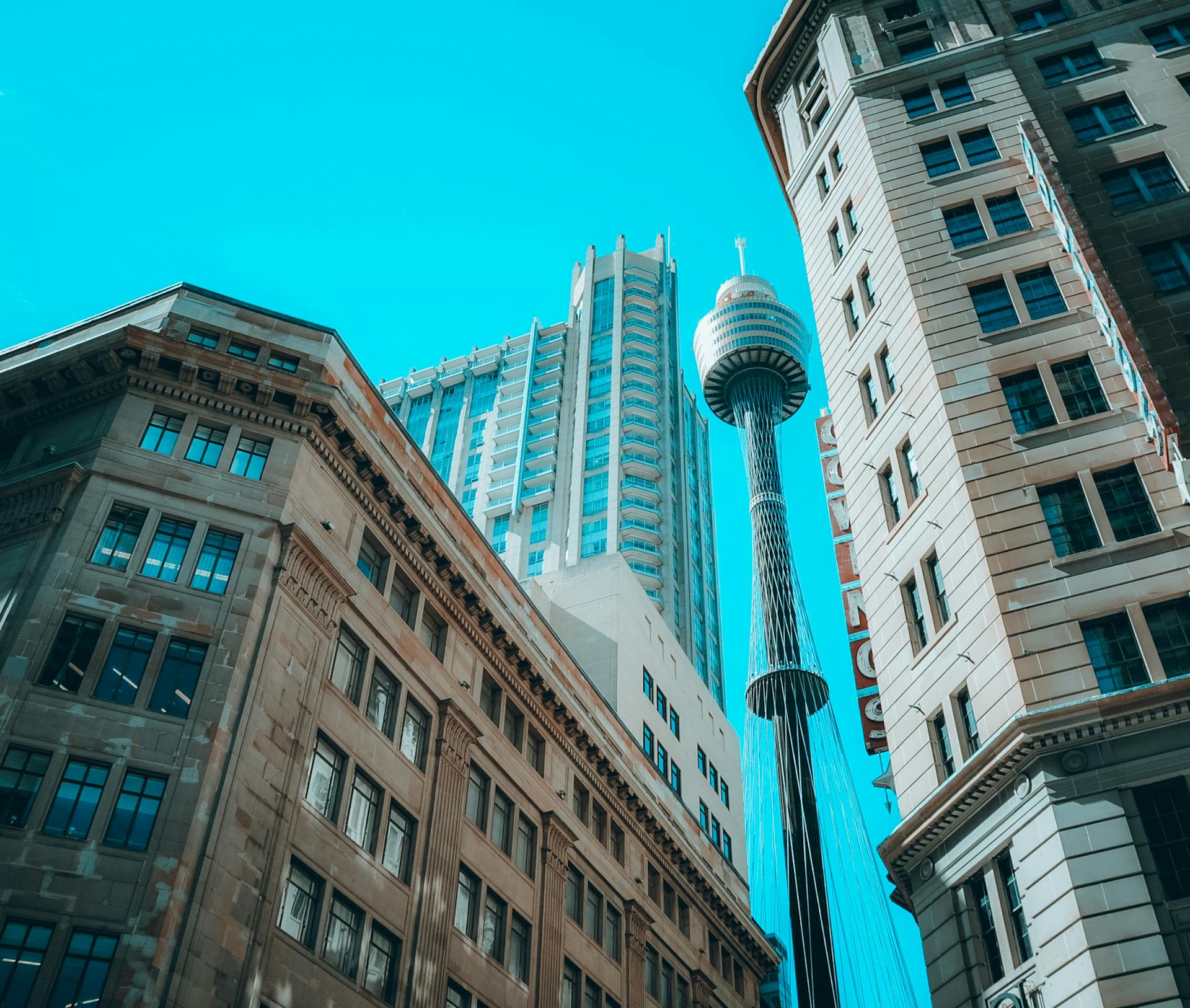 Low angle view of Sydney's modern skyscrapers and Sydney Tower under clear blue skies.