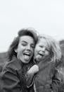 Grayscale Photo of Mother and Daughter with Their Tongues Out