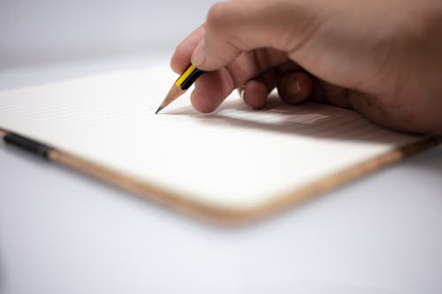 Close-Up Shot of a Person Writing on a Notebook