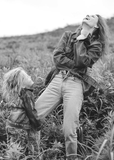 Heartwarming scene of a mother and daughter laughing in denim outfits outdoor.