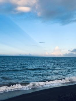 Peaceful seaside scene with waves crashing on the shore under a clear blue sky.